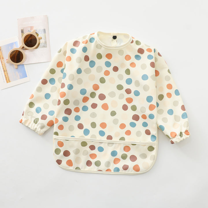 Polka dots waterproof long-sleeved cape bib with elastic cuffs and catch-all front pocket, laid flat on a neutral background – ideal for messy meals and toddler crafts