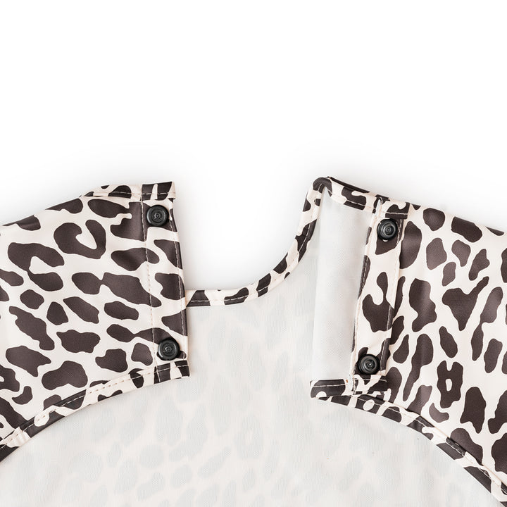 black and white waterproof long-sleeved cape bib with elastic cuffs and catch-all front pocket, laid flat on a neutral background – ideal for messy meals and toddler crafts